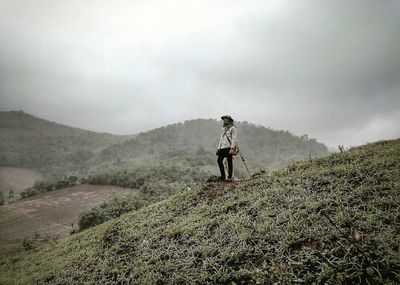 Man standing on mountain against sky and fog