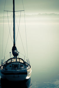 Sailboats moored on sea against sky