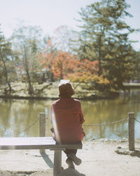 Rear view of man standing by railing against lake