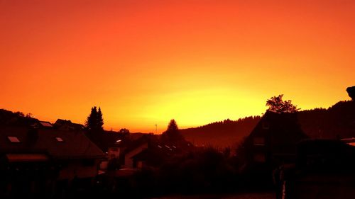 Silhouette houses against clear sky during sunset