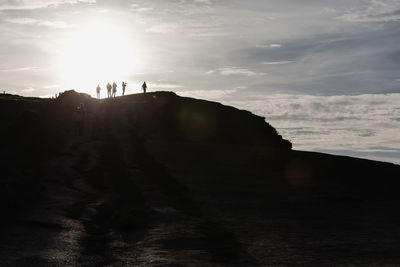 Low angle view of silhouette people on cliff against sky