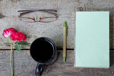 Directly above view of black coffee with diary and eyeglasses on table
