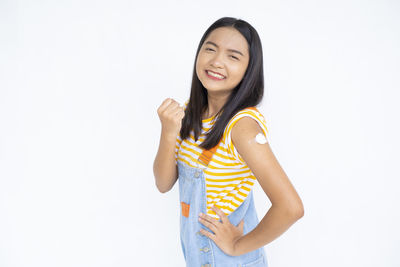 Smiling young woman standing against white background