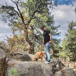 Side view of man with dog standing on rock in forest