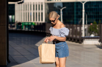 A young woman visited shops, checks purchases in a paper bag