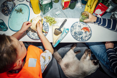 High angle view of father drinking while son eating banana at table