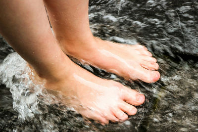 Low section of woman feet in water