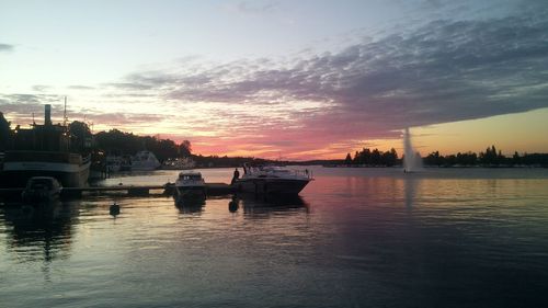 Boats moored in city at sunset