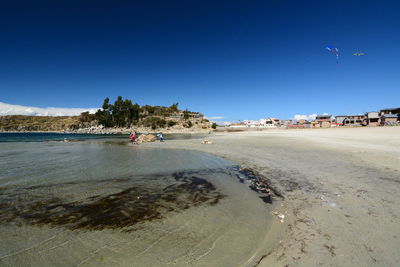 Scenic view of beach against clear blue sky