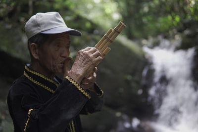  dusun ethnic grandpa , sabah, plays traditional bamboo musical instruments 