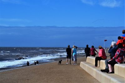 People at beach against blue sky