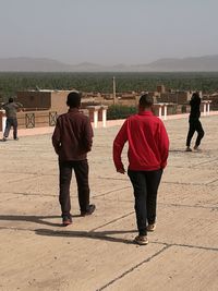 Rear view of people standing against clear sky