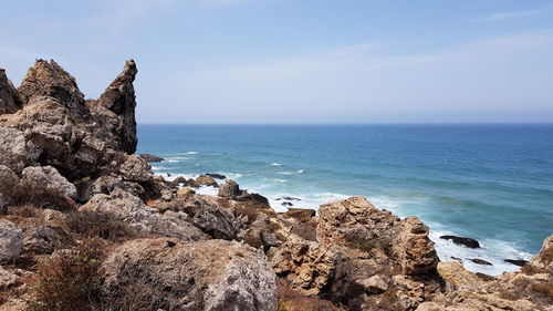 Scenic view of rocks on beach against sky