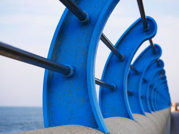 Close-up of machine part by sea against sky