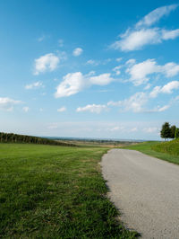 Road amidst field against sky