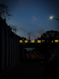 Illuminated street against sky at night