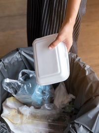 Midsection of person throwing garbage in can