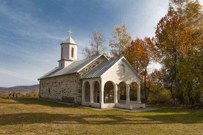 Church by building against sky during autumn