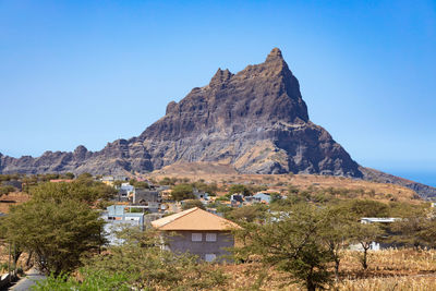 Built structure on rocky mountain against clear blue sky