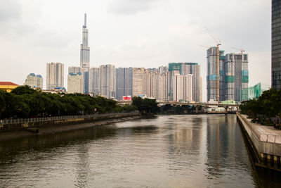 River by modern buildings against sky in city