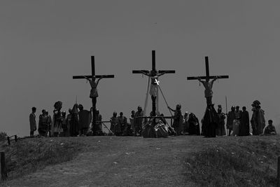 Low angle view of people crucified on cross against sky