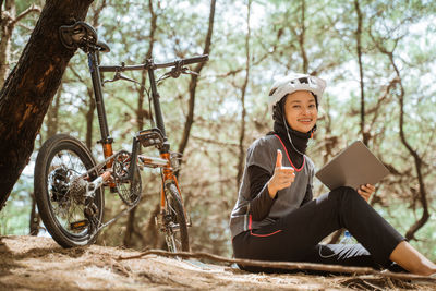 Portrait of young woman listening music while sitting in forest