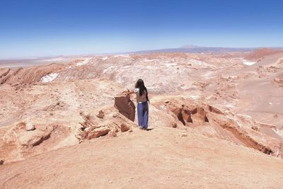 Woman standing on rock against sky