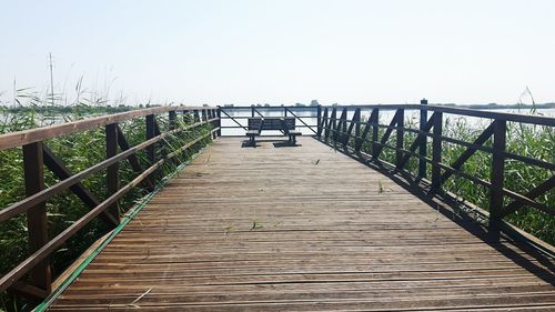 Empty wooden pier on sea against clear sky