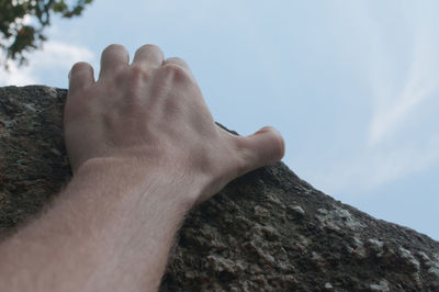 Midsection of person on rock against sky