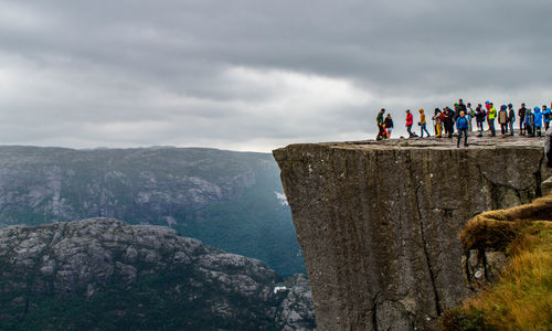 People standing on rock by mountains against sky
