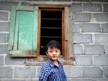 Portrait of boy standing against wall