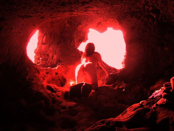 Naked woman kneeling in cave