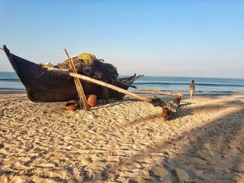 Boat moored on beach against clear sky