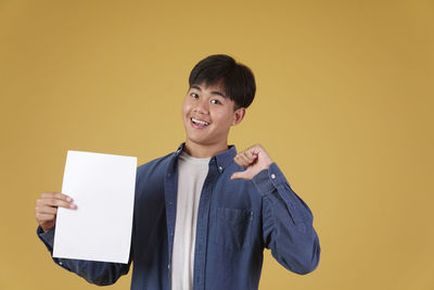 Portrait of smiling man standing against yellow background