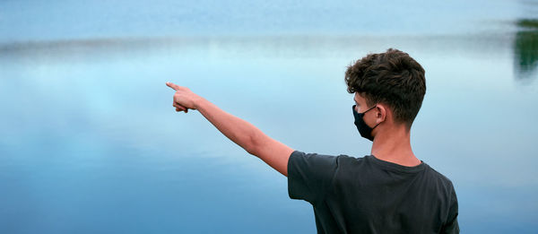 Rear view of boy wearing mask standing by lake