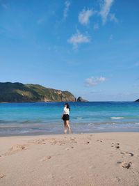 Woman walking on beach against sky