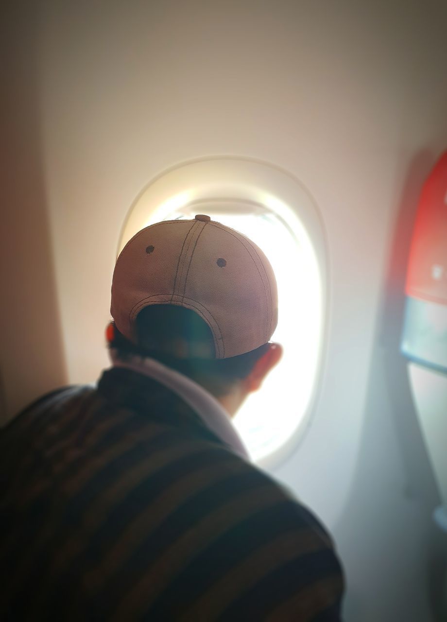 REAR VIEW OF MAN LOOKING AT AIRPLANE