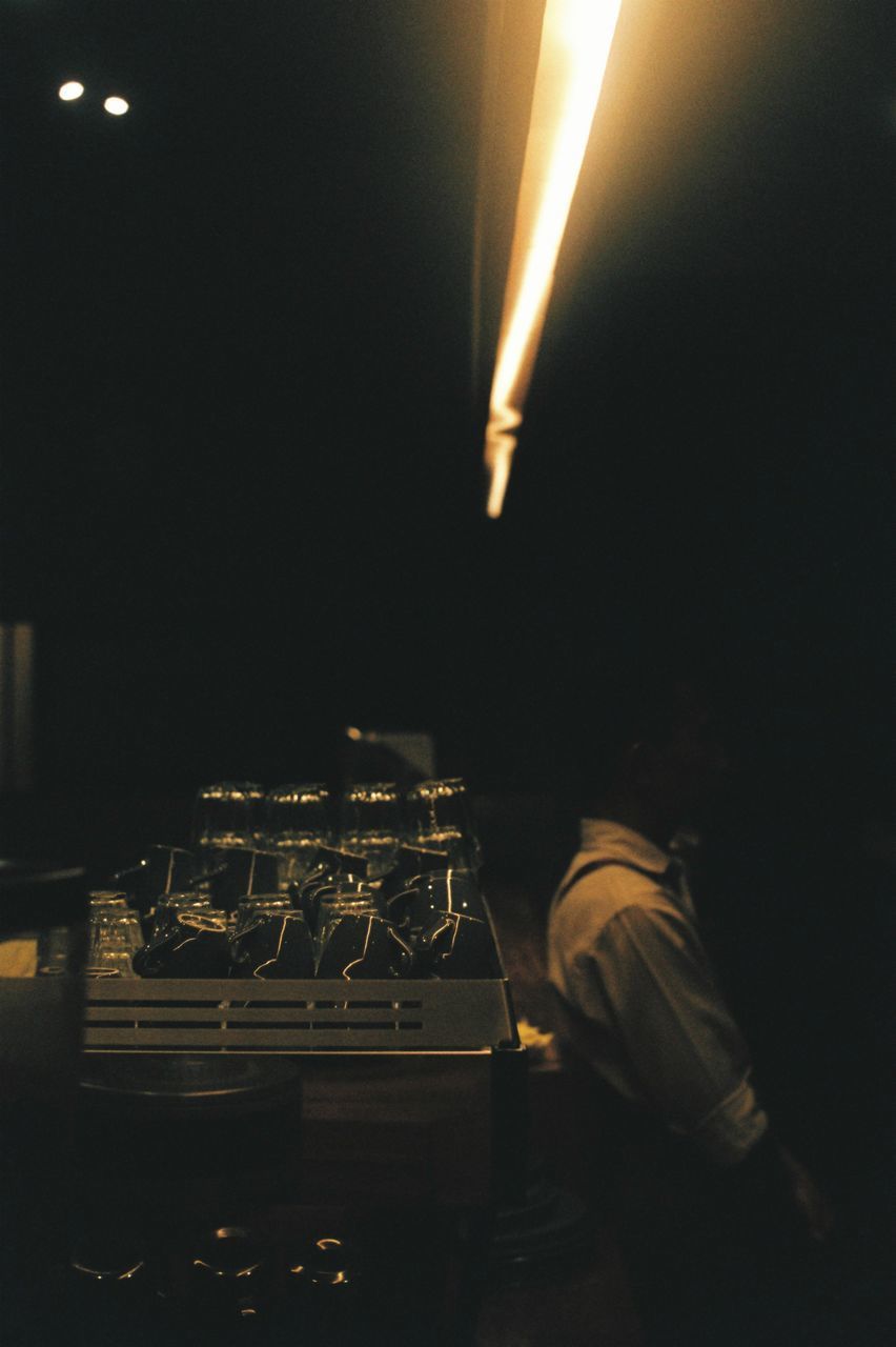 REAR VIEW OF MAN ON ILLUMINATED STAGE