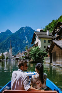 Rear view of people on buildings by mountain against sky