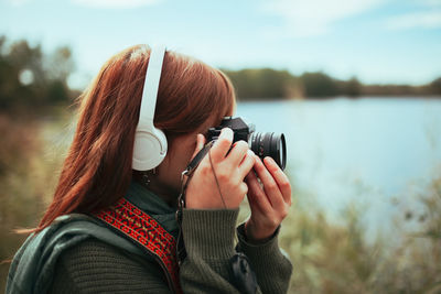 Close-up of young woman photographing by lake