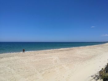 Scenic view of beach against clear blue sky