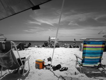 Deck chairs on beach against sky