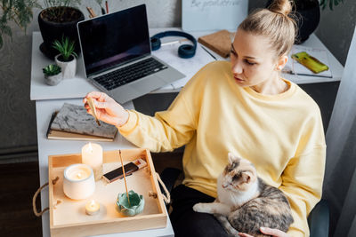 Mental health and work. work life balance. young woman with cat lighting candles, relaxing and