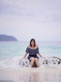 Full length of young woman at beach against sky