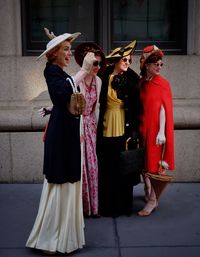 Female friends in old-fashioned clothes standing on sidewalk