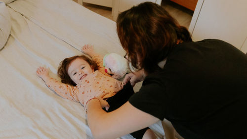 Mom changes clothes for a baby girl with a cast on her leg.