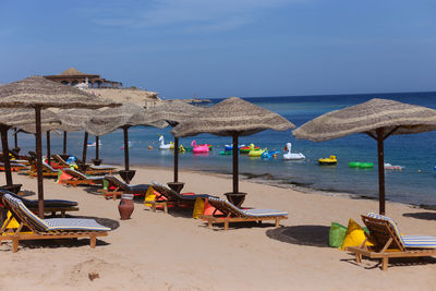 Lounge chairs and parasols on beach against sky