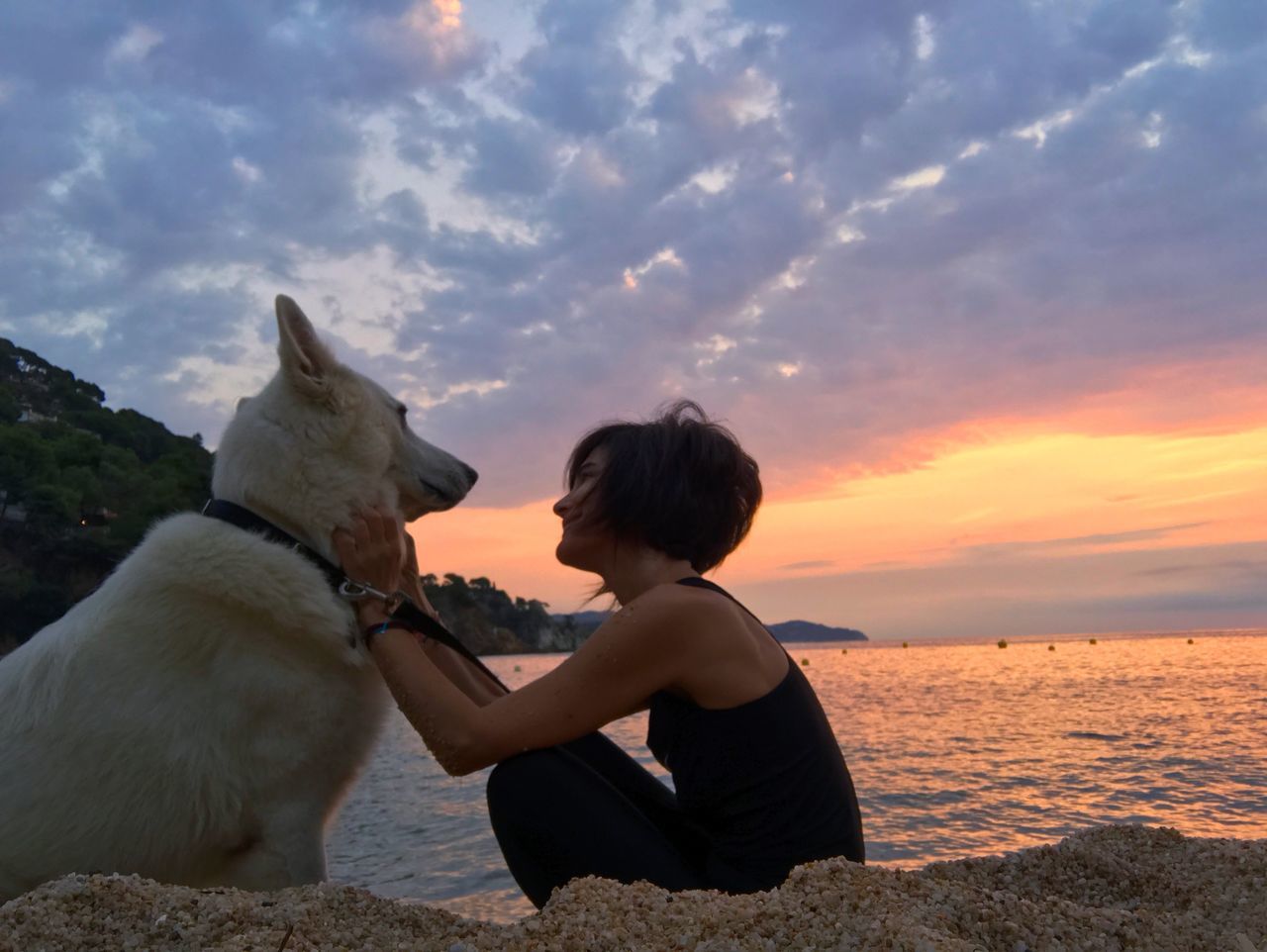 sunset, real people, one animal, sky, one person, pets, domestic animals, sitting, dog, leisure activity, animal themes, mammal, outdoors, sea, nature, lifestyles, horizon over water, beauty in nature, friendship, day, young adult, people