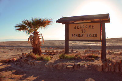 Information sign in desert by sea against clear sky