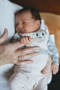 Great granddaughter holding the finger of her great grandmother, close-up